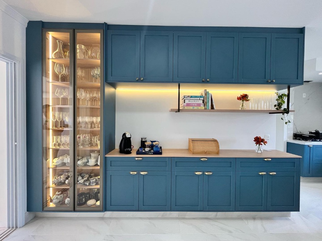 Armário cristaleira planejado em azul com luzes LED e bancada amadeirada.