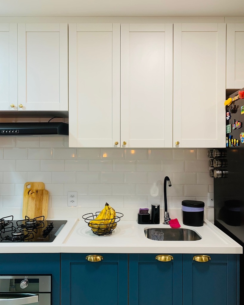 Cozinha planejada estilo provençal com armários shaker azul e puxadores dourados.