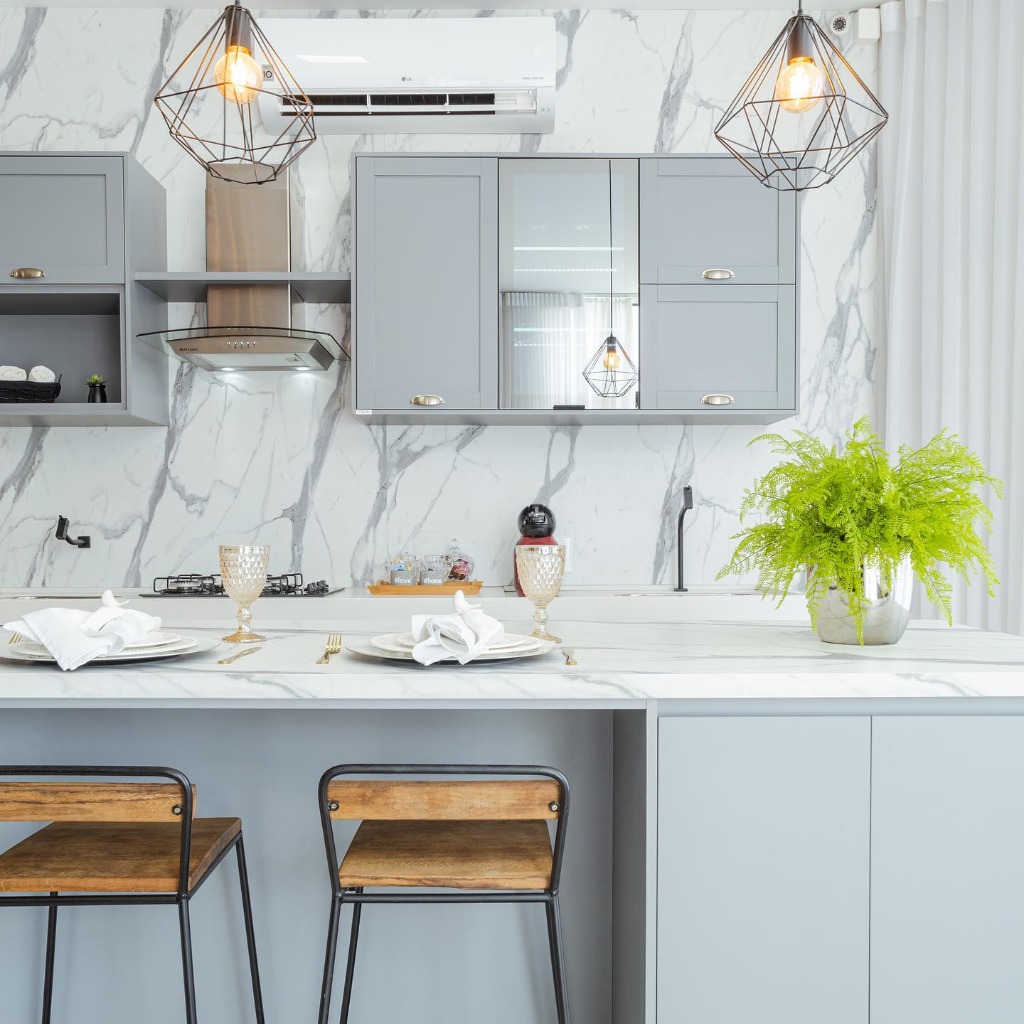 Cozinha gourmet planejada com ilha de mármore e banquetas.
