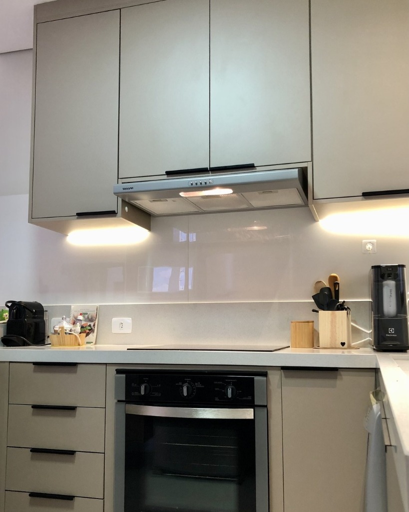 Cozinha planejada com cooktop de indução, forno de embutir e bancada em quartzo branco.