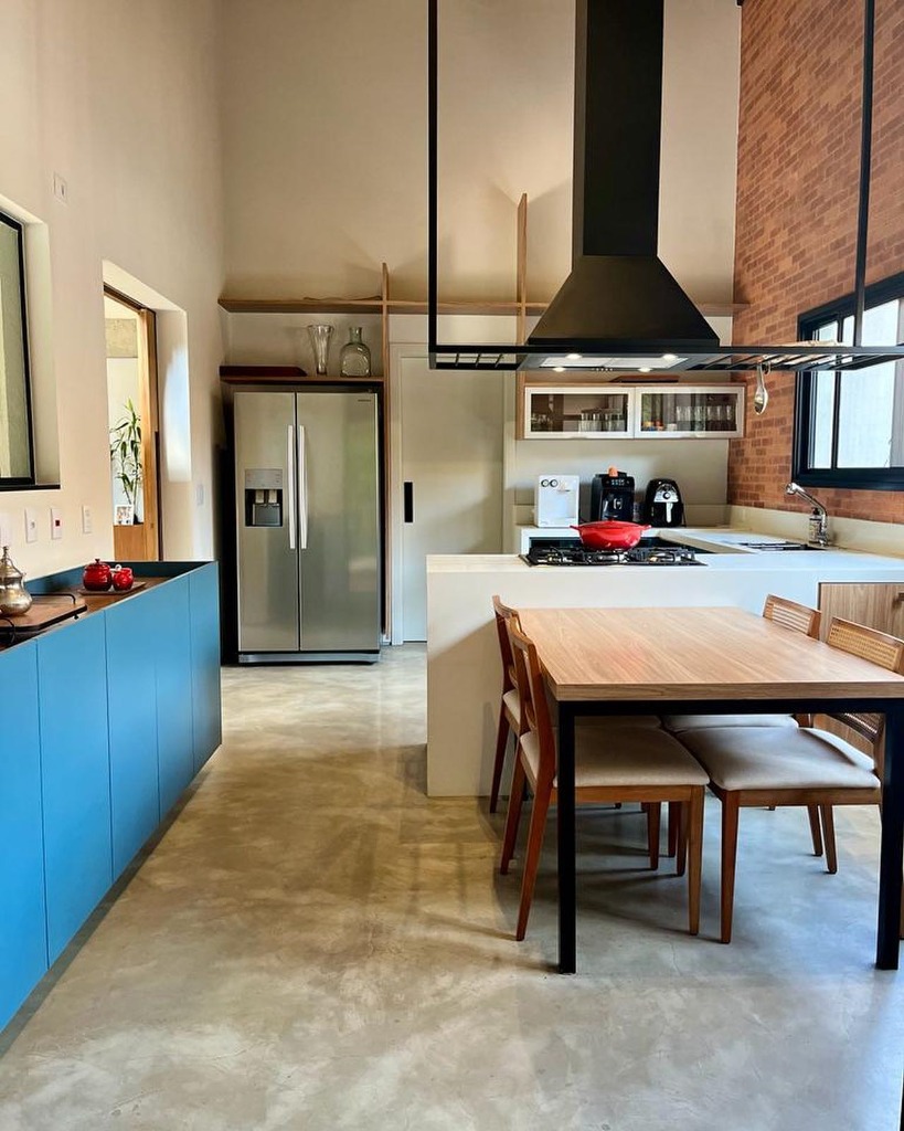 Cozinha planejada estilo industrial com tijolos aparentes e mesa de jantar.